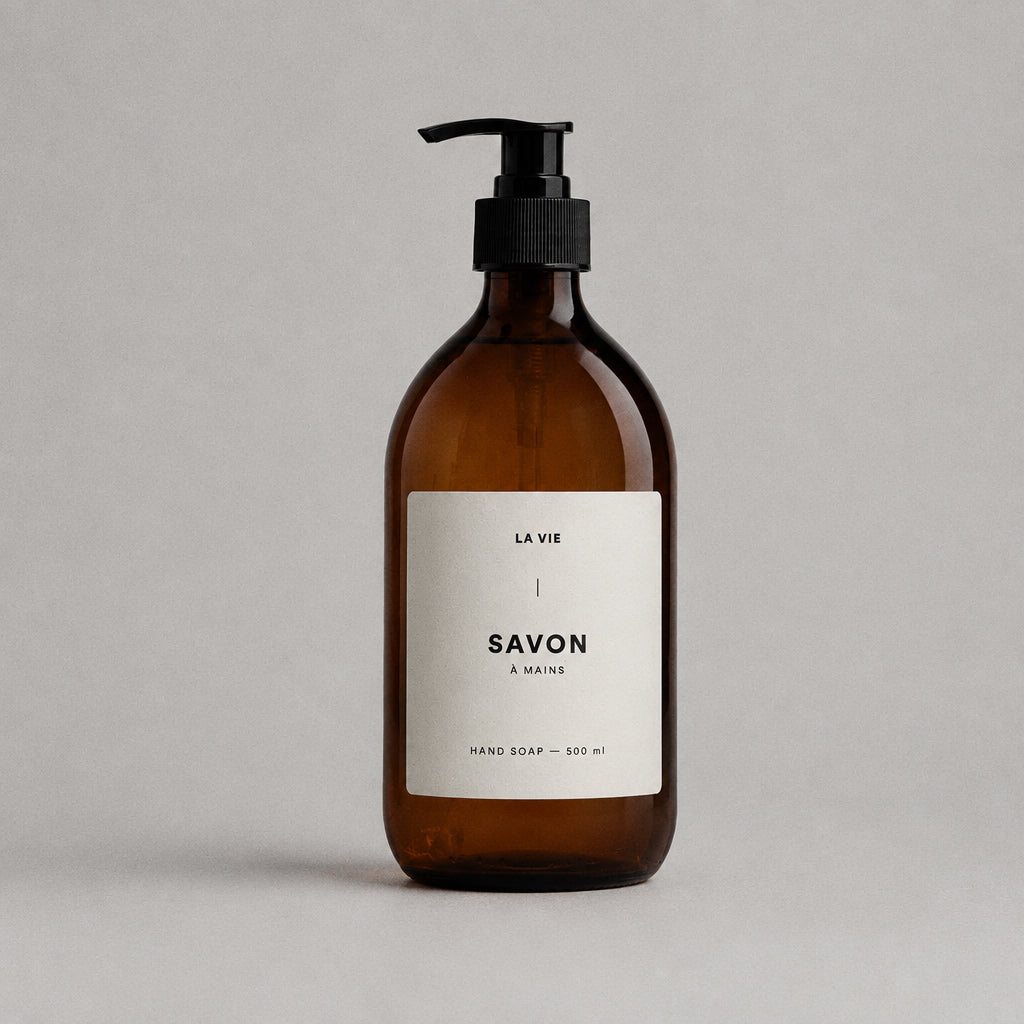 Brown soap bottle with pump on a stone surface against a brown background